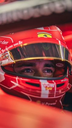 a close up of a person wearing a racing car helmet and looking at the camera