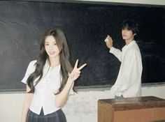 two young people standing in front of a blackboard