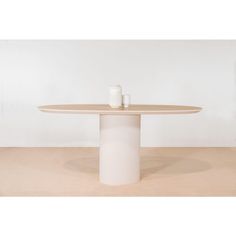 a table with two cups on it and a white wall in the backround