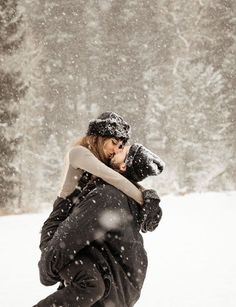 a woman walking through the snow carrying a dog on her back