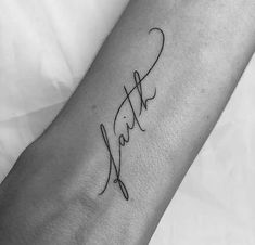 a black and white photo of a person's arm with the word faith written in cursive writing