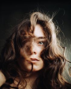 a woman with long hair is posing for the camera, her eyes are open and she has frizzy hair on her head