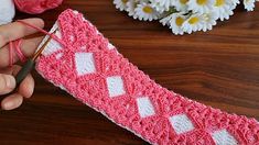 someone is crocheting a piece of pink and white knitted fabric with scissors