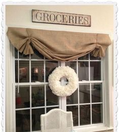 a white chair sitting in front of a window with a wreath hanging on it's side