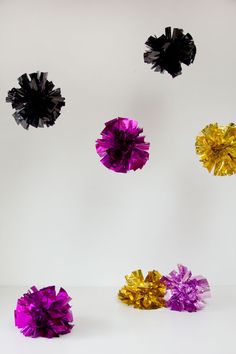 four different colored pom poms are flying in the air