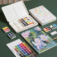 an assortment of art supplies including watercolors, paints and pencils on a table