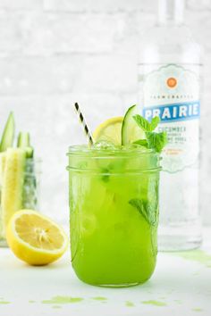 a green drink with lemons, cucumber and mint on the table next to it