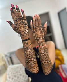 a woman is holding her hands up with henna tattoos on it