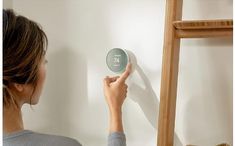 a woman is pressing the button on a wall