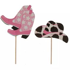 two pink and black cowboy hats on top of wooden sticks with white stars in them