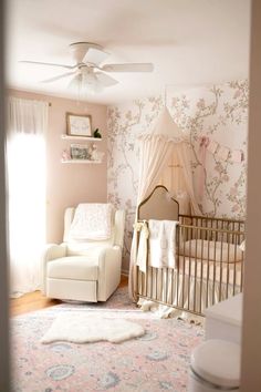 a baby's room with floral wallpaper and a white chair in the corner