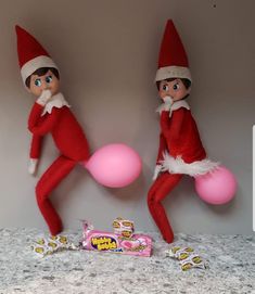 two elfs are playing with pink balls on the counter next to a candy bar