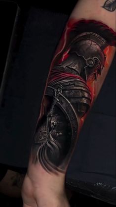 a man's arm with a roman soldier tattoo on it and red flames coming out of his helmet