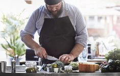 a man in an apron is preparing food on a counter top with utensils