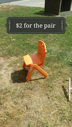 an orange plastic chair sitting on top of a grass covered field