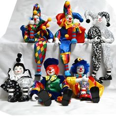 a group of clowns sitting next to each other on a white sheeted surface