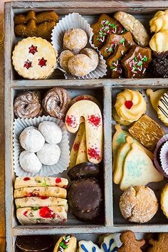 an open box filled with lots of different types of cookies and pastries on top of a wooden table