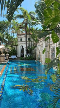 an outdoor pool surrounded by palm trees and blue tiles with fish swimming in the water