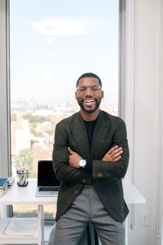 a man standing in front of a window with his arms crossed and looking at the camera