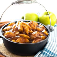 apples are in a bowl with caramel sauce on the table next to green apples