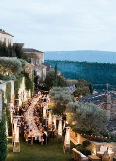 an outdoor dinner is set up on the lawn in front of some buildings and trees