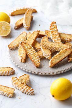 lemon meringue cookies on a plate next to sliced lemons and two lemon wedges