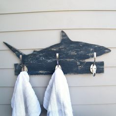 two towels hanging from hooks on the side of a house next to a shark shaped coat rack