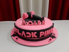 there is a pink cake with black letters on it