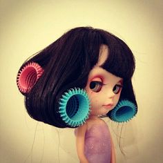 a close up of a doll with hair dryers on her head and black hair