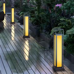 some lights that are on the side of a wooden floor in front of plants and trees