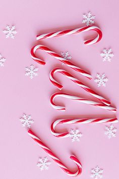 some candy canes and snowflakes on a pink background