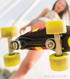 a skateboard with yellow wheels hanging from it's end and a girl in the background