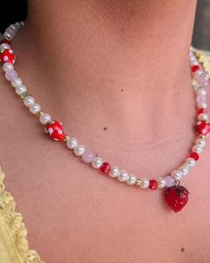 a close up of a person wearing a necklace with beads and a strawberry on it