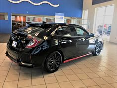 a black car parked in a showroom with its hood up and luggage strapped to it's back