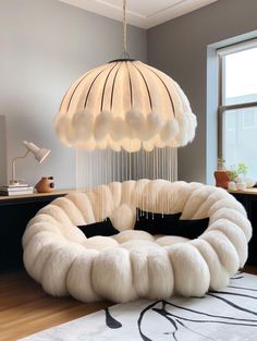 a large white chair sitting on top of a wooden floor next to a lamp shade