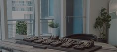 a table with chess pieces on it in front of large windows and potted plants