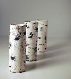 three white vases sitting on top of a table