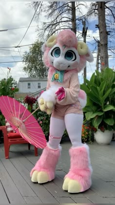 a person dressed as a monster holding an umbrella and standing on a deck next to some potted plants