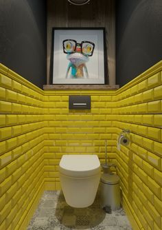 a bathroom with yellow brick walls and a white toilet in the corner, next to a painting on the wall