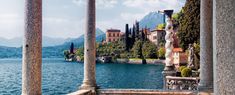 an outdoor area with columns, water and mountains in the backgrouds is shown