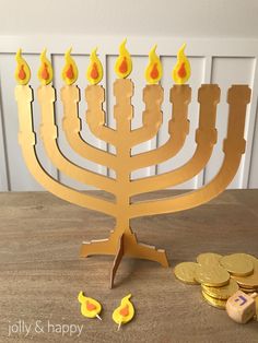 a wooden menorah with lit candles and gold coins on a table next to it