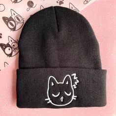 "Cute sleepy cat embroidered beanie, perfect for a cat lover looking for a fun way to express themselves! Make your hat unique by upgrading to the glow in the dark thread option! The Cat emoji caps are perfect for any occasion and would also make a great gift for a friend or relative! You could expect beautiful embroidery of our own hand drawn designs, embroidered by us, on a soft, high quality beanie! ☆ There may be a slight difference on every item that will make your items special and one of Casual Cat Ears Beanie For Winter, Casual Warm Beanie With Cat Ears, Casual Knitted Beanie With Cat Ears, Casual Beanie With Cat Ears, Cute Fitted Beanie For Winter, Cute Fitted Winter Beanie, Casual Cat Design Beanie Hat, Casual Beanie Hat With Cat Design, Casual Beanie With Cat Design