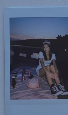 a woman sitting on top of a bed next to a cake