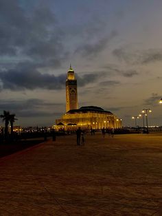 people are walking around in front of a building with a clock tower at night time