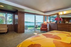 a bedroom with a bed, chair and large window overlooking the water in front of it