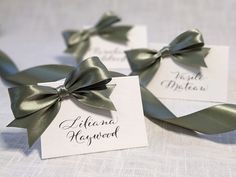 three place cards with green bows on them