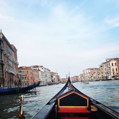 a boat traveling down a river next to tall buildings and water front homes on either side