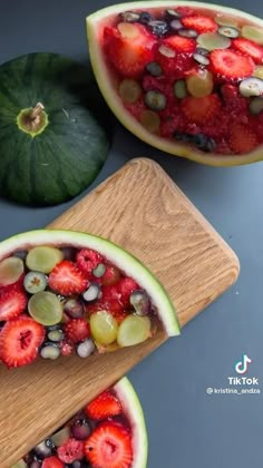 two slices of watermelon with strawberries and olives on top, one cut in half