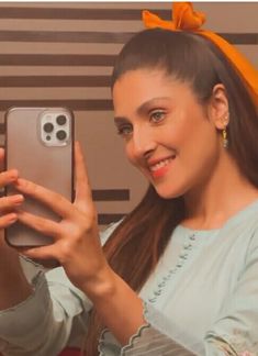 a woman taking a selfie with her cell phone in front of her face and smiling at the camera