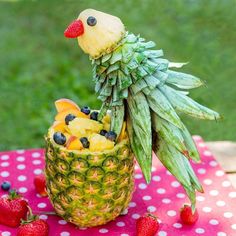 a pineapple with blueberries and strawberries in the shape of a bird sitting on top of it